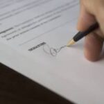 Mano de una persona firmando un documento