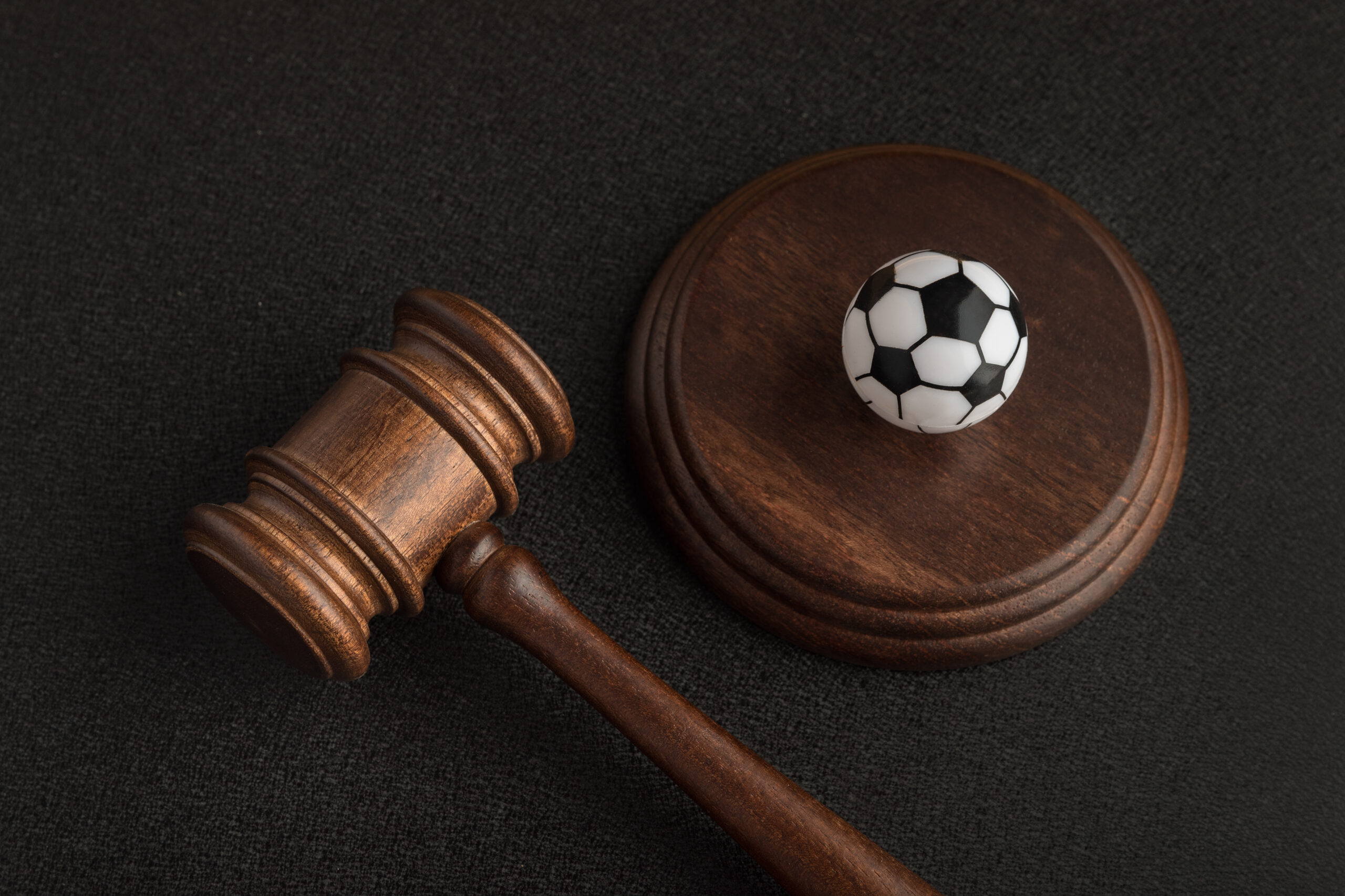 Wooden judge gavel and toy soccer ball. Football coach accused. Concussion lawsuit